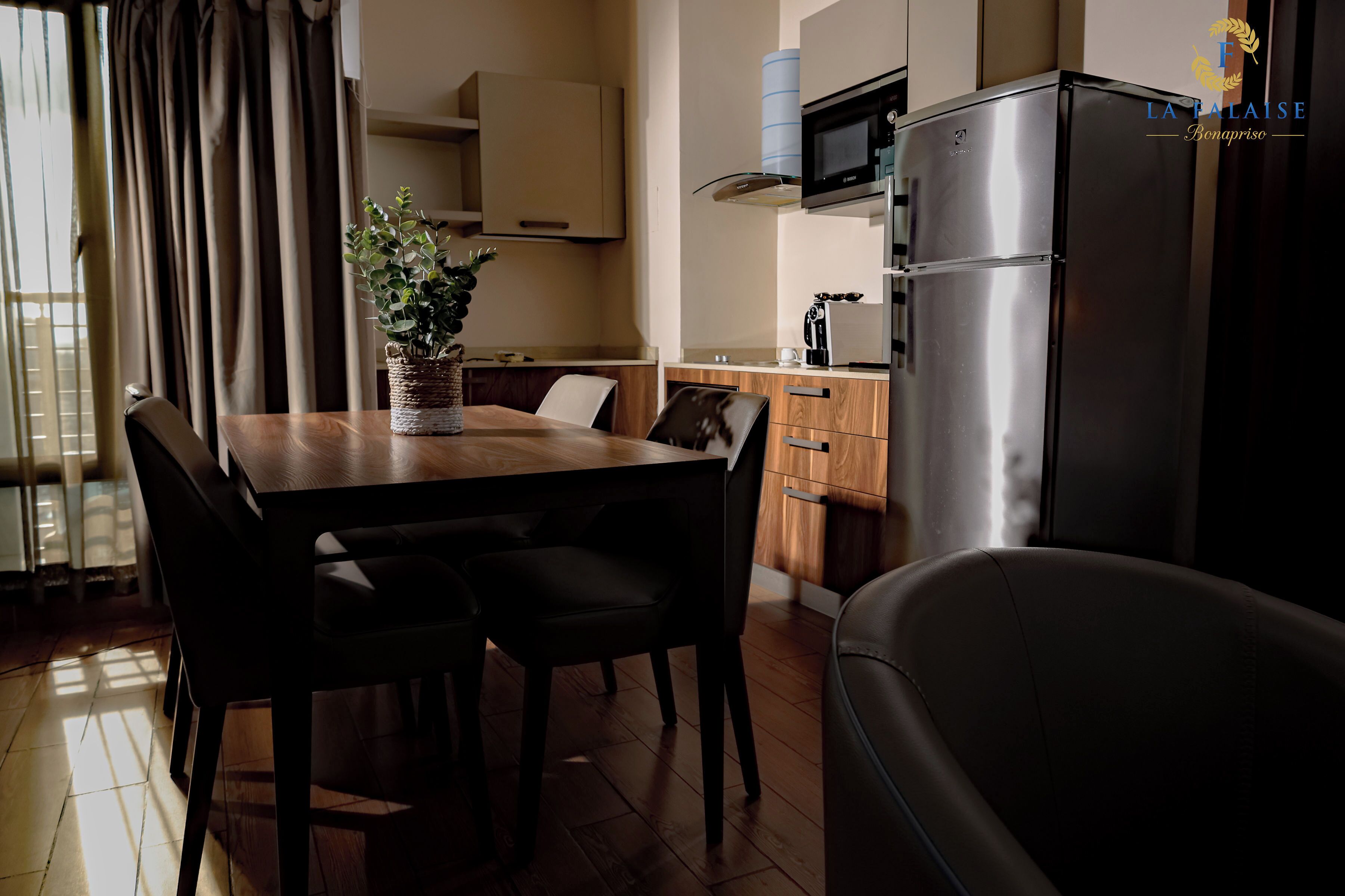 A modern kitchen with a dining table, chairs, a refrigerator, and a microwave.