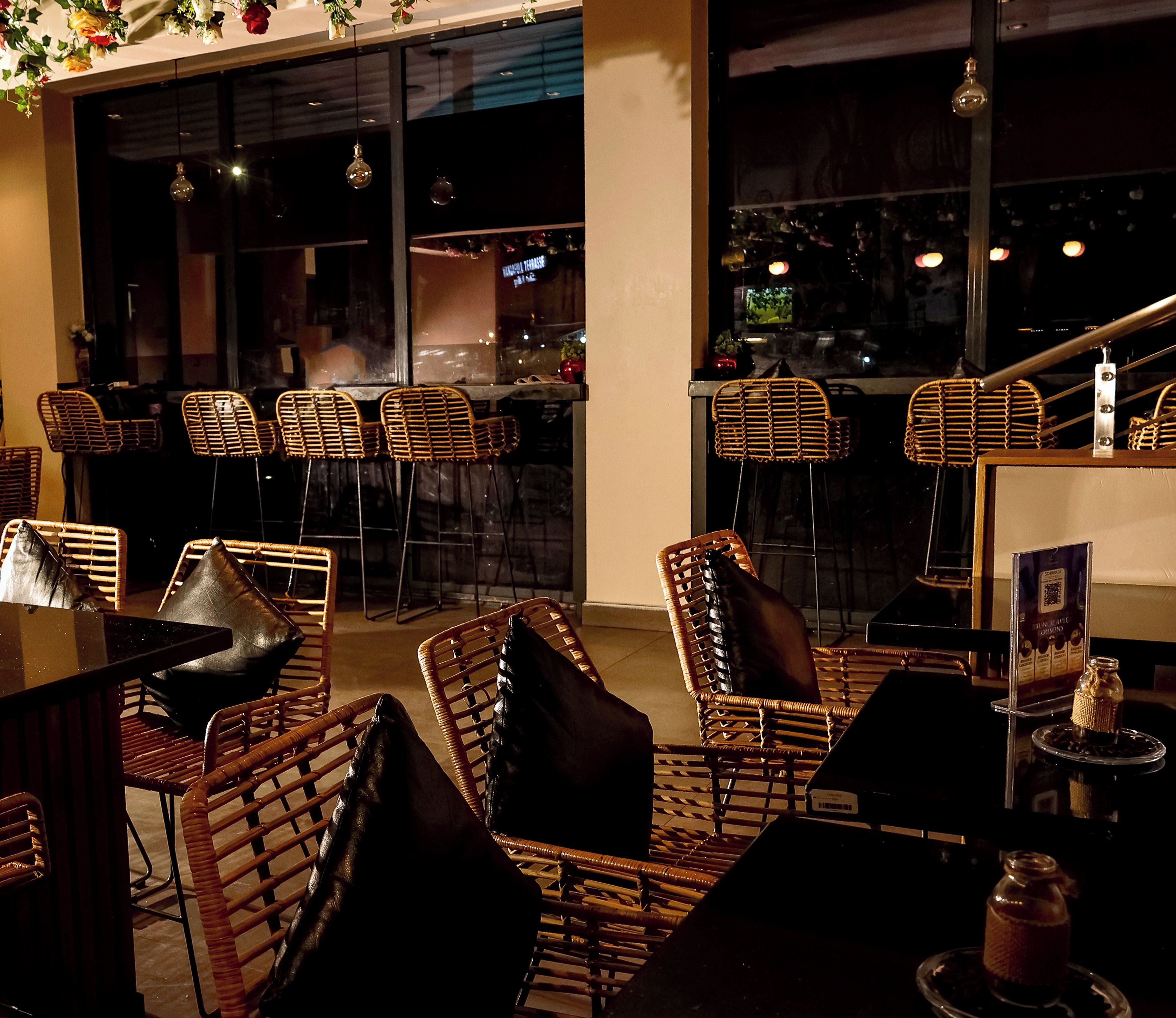 Un espace extérieur aménagé avec des chaises et des tables en osier, un piano et une vue sur la rue.