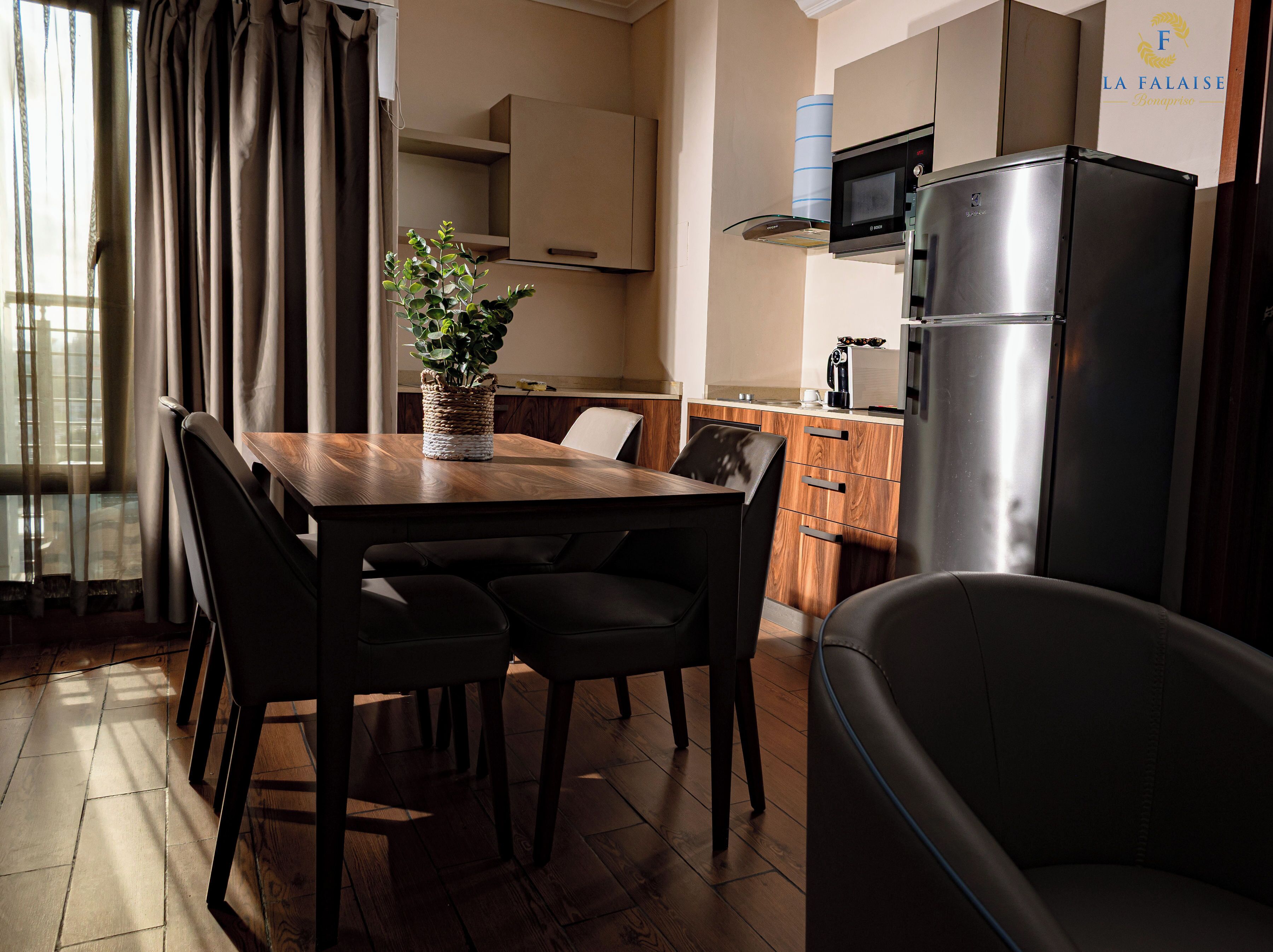 A modern kitchen with a dining table, chairs, a refrigerator, and a microwave.
