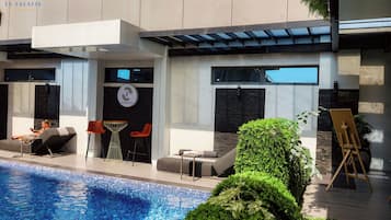 Una piscina al aire libre, sillones reclinables de piscina