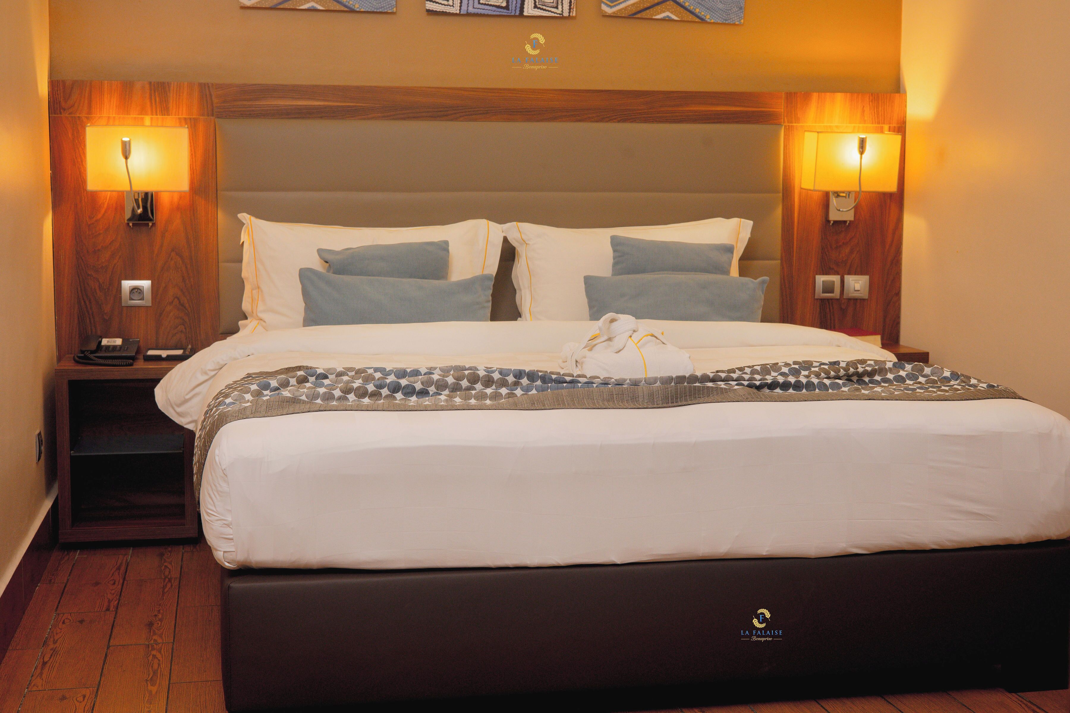 A hotel room with a large bed, two bedside tables, and wall-mounted lamps.
