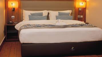 A hotel room with a large bed, two bedside tables, and wall-mounted lamps.