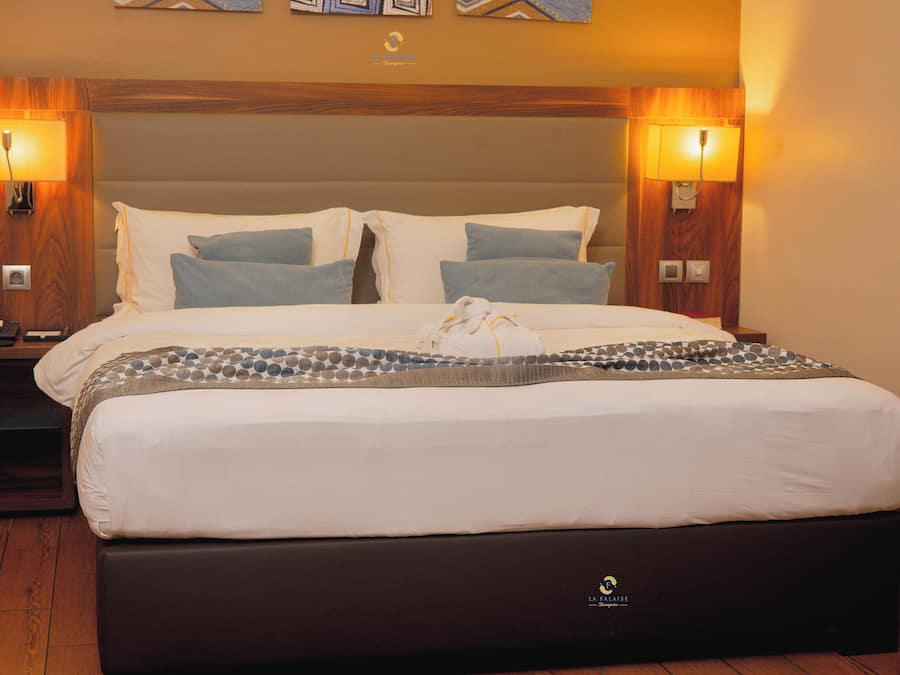 Habitación de hotel con una cama grande, dos mesitas de noche y lámparas fijadas a la pared.