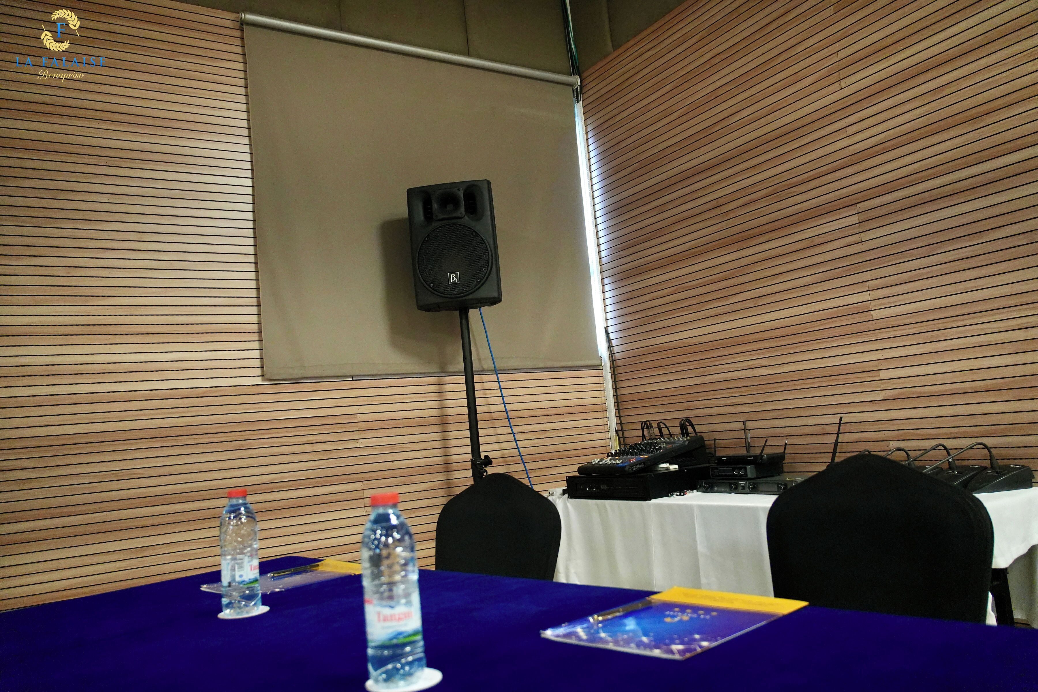 A conference room with a table, two water bottles, a speaker, and audio equipment.