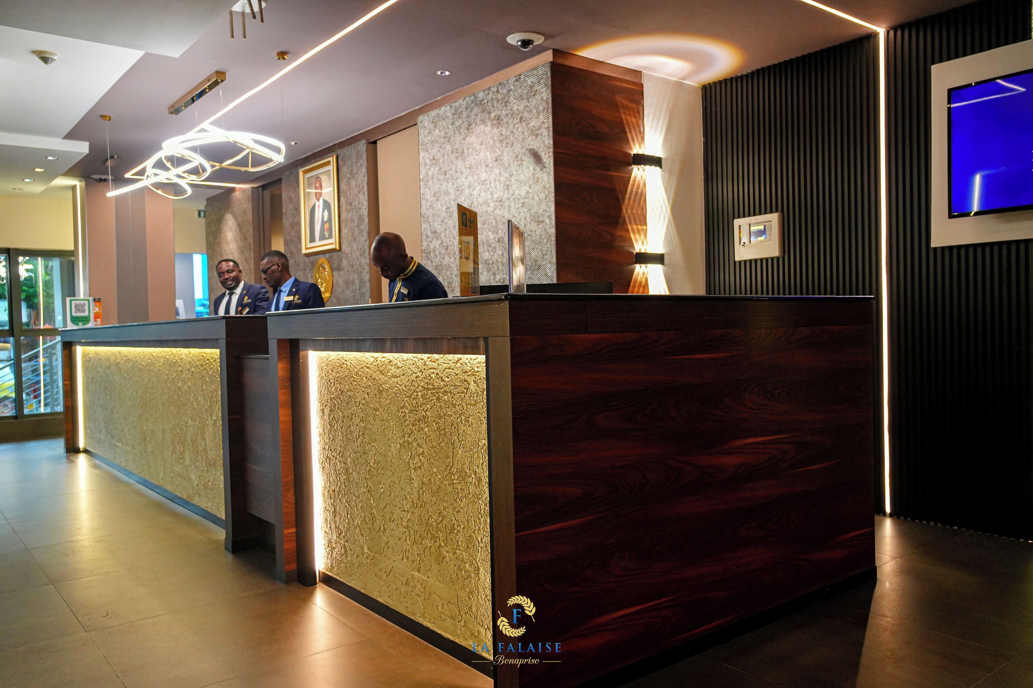 Un comptoir d’accueil au design moderne, doté d’un revêtement en bois et d’un mur à texture. Un téléviseur est fixé au mur, sur la droite.