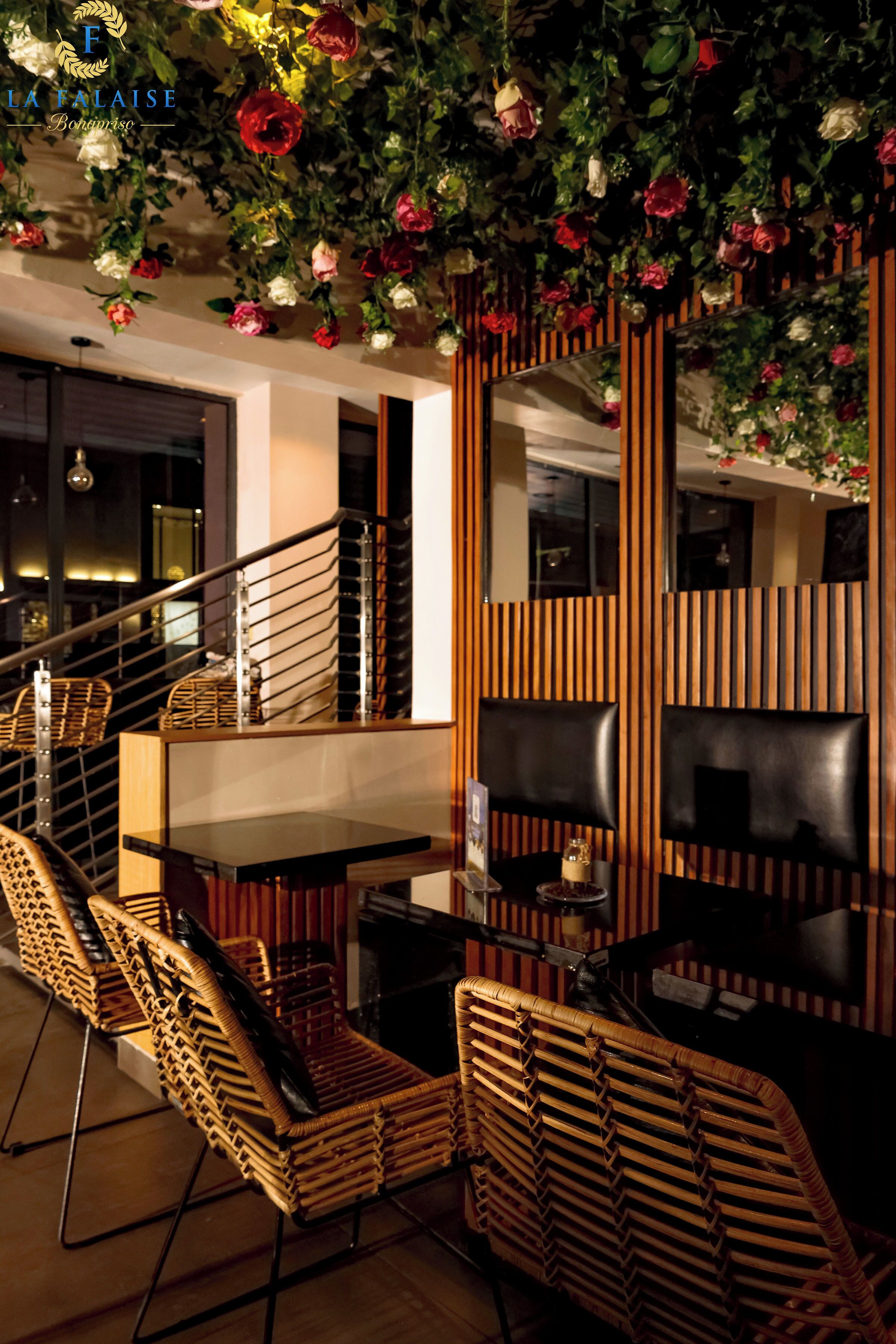 A modern interior with a staircase, wicker furniture, and a decorative wall with floral arrangements.