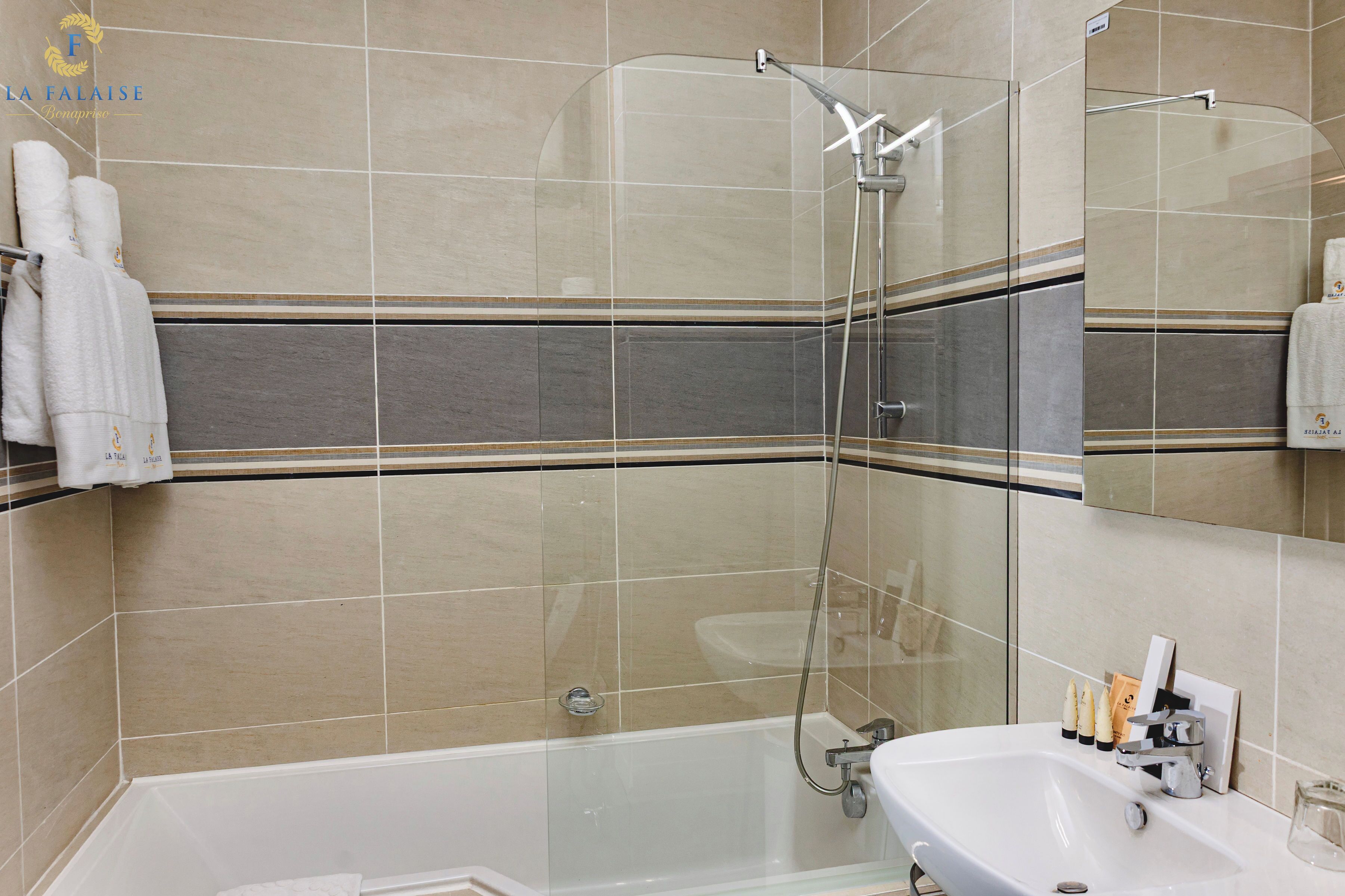 Un baño moderno con ducha envuelta en vidrio, una bañera blanca y un tocador con artículos de aseo.