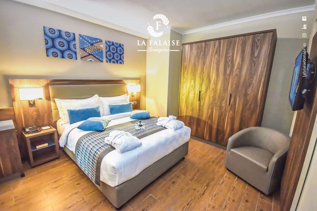 A hotel room with a bed, bedside lamps, a wardrobe, and a chair.
