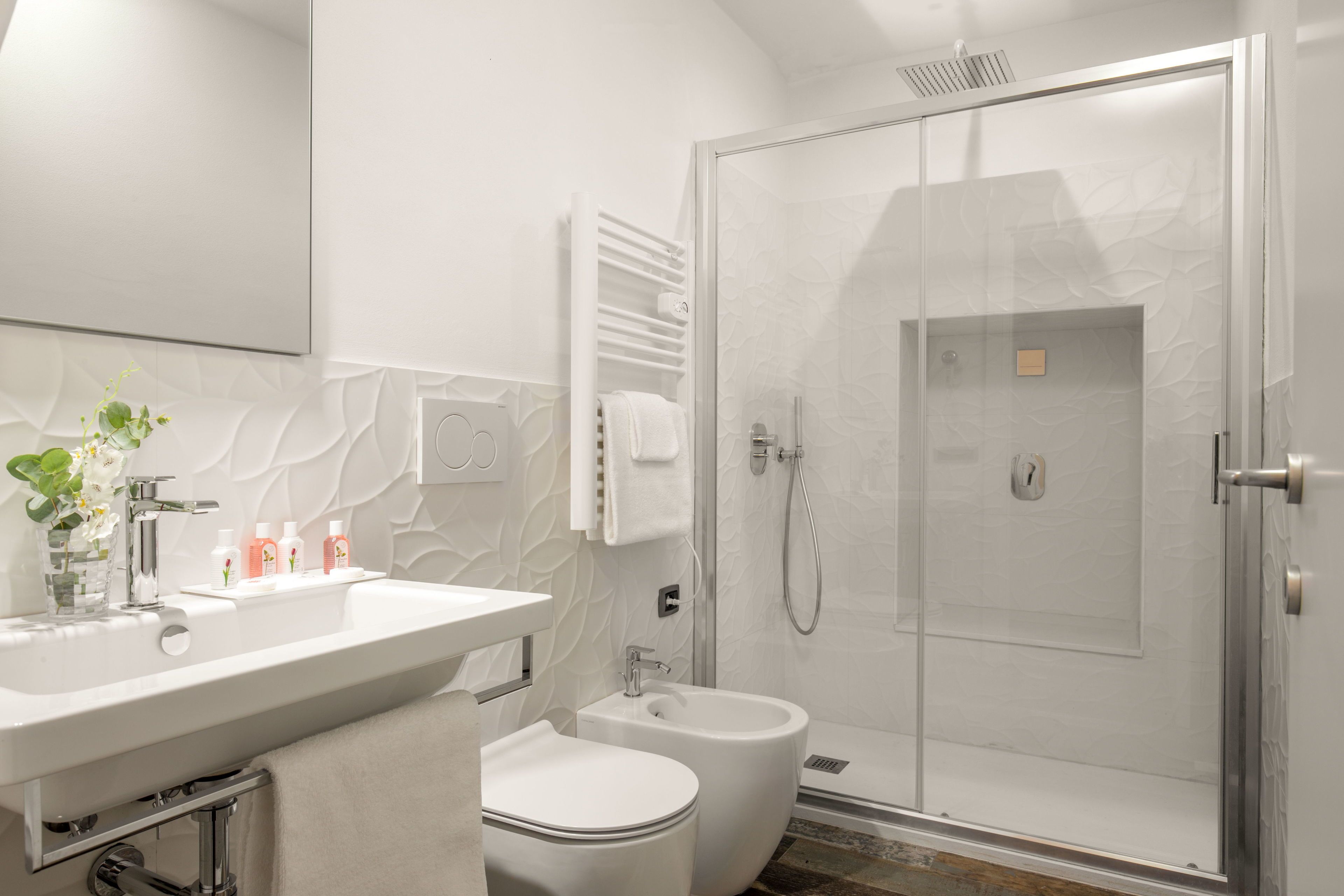 Une salle de bain moderne équipée d’un lavabo, de toilettes, d’un bidet et d’une douche à parois de verre.