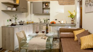 A modern kitchen with a dining area, featuring a glass table, a sofa, and a brick wall. - MySuite Tower Pantheon (Rome)