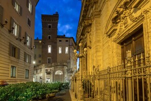 Una calle estrecha con edificios históricos, puertas de hierro ornamentales y un cielo despejado.