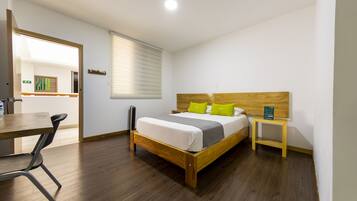 Una habitación de hotel moderna con una cama de madera, una mesita de noche pequeña, un escritorio y una silla.