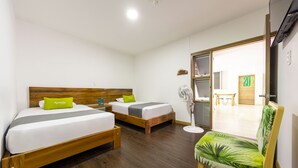 A hotel room with two beds, a wooden headboard, a green chair, and a fan. - Ayenda Marckia 1901 (Armenia)
