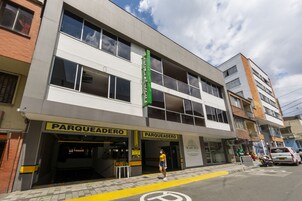 A multi-story building with 'PARQUEADERO' signage, a visible entrance, and a 'MARCAIA' hotel sign.