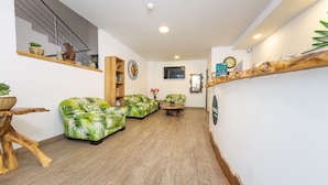 A modern interior with a wooden floor, a sofa with a tropical print, a wooden coffee table, and a shelf with decorative items. - Ayenda Marckia 1901 (Armenia)