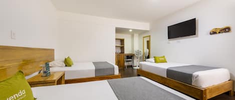 A hotel room with two single beds, a TV mounted on the wall, and a wooden headboard.
