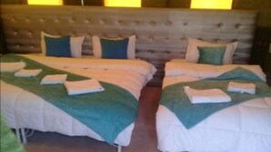 A hotel room with two beds, each with neatly folded towels and green throw blankets. - Merzouga Experience Camp (Taouz)