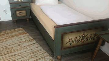 A bedroom with a single bed, a nightstand, a lamp, and a patterned rug.