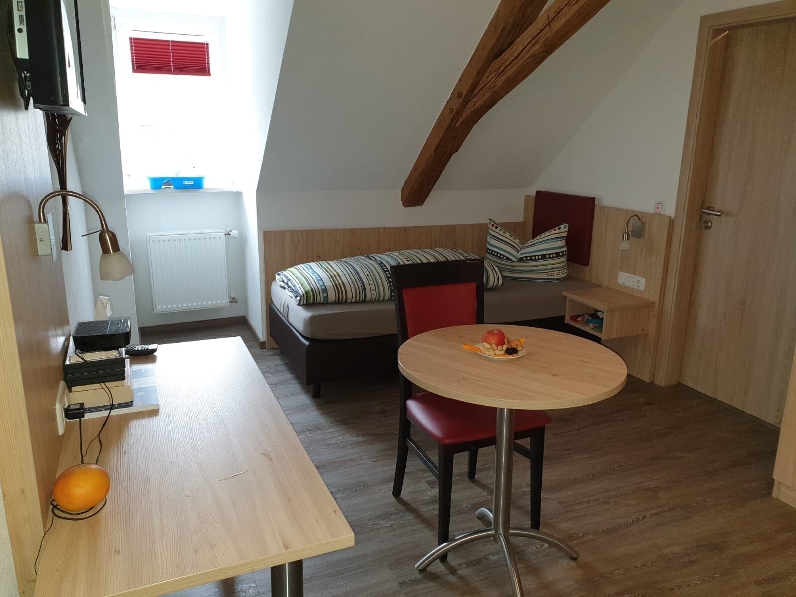 Um espaço de estar compacto com uma mesa de madeira, um sofá, uma mesinha redonda com frutas e uma área de cozinha compacta.