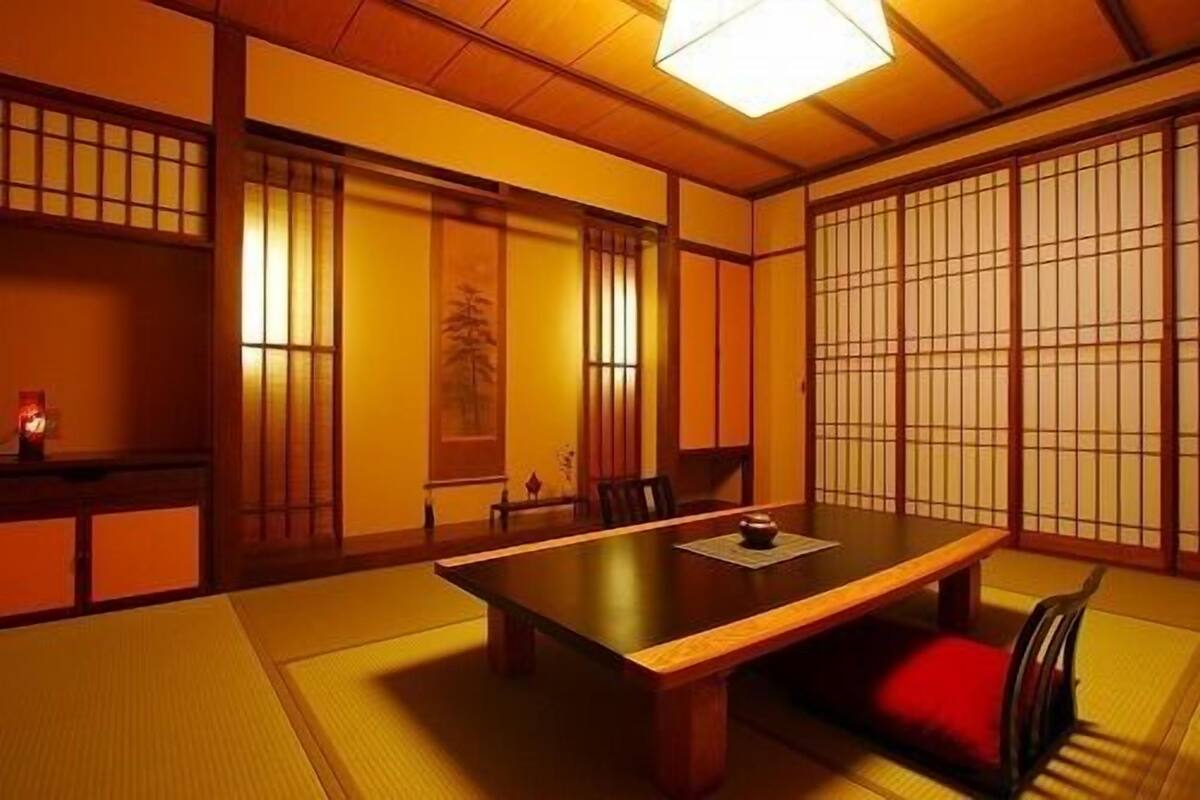 A traditional Japanese room with tatami flooring, a low table, and sliding doors.