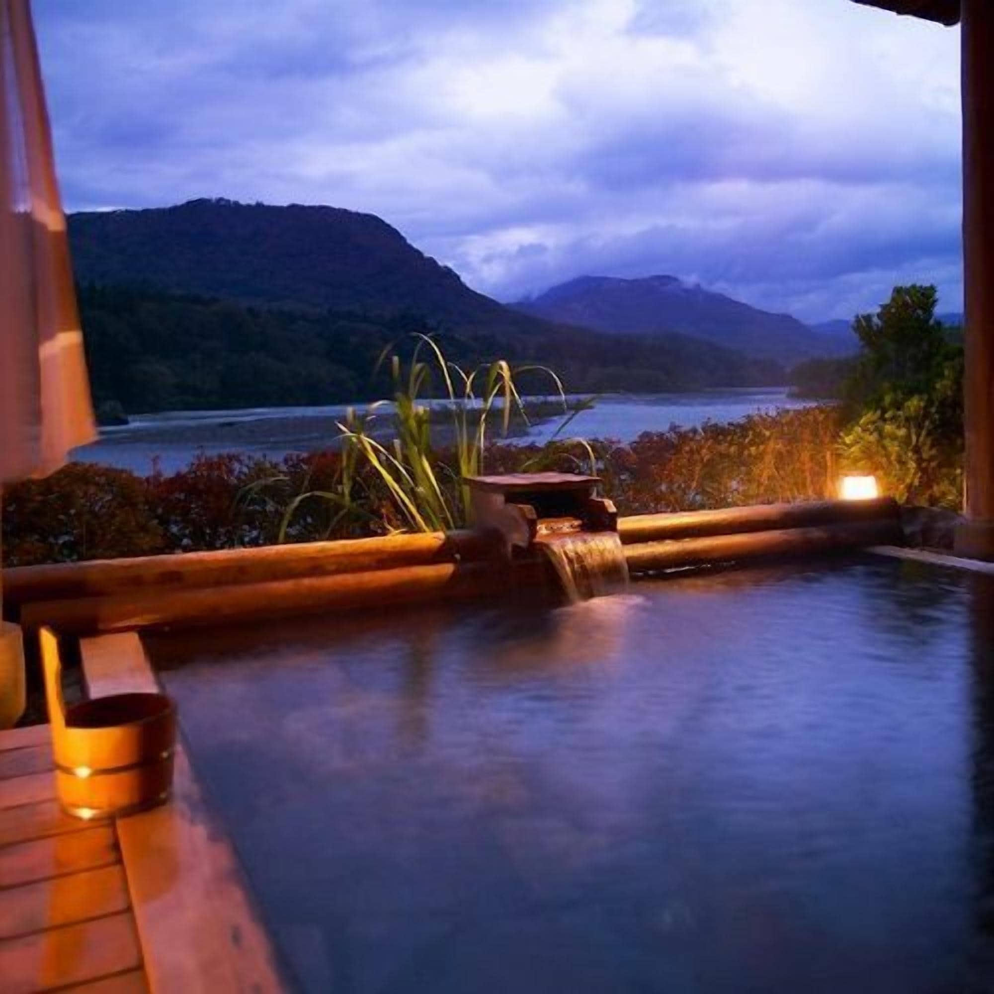 A hot tub with a view of a lake and mountains.