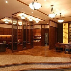 Un interior japonés tradicional con suelo de madera, esteras de tatami y una mesa baja con sillas.