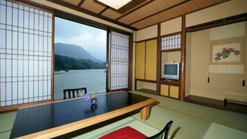 Une pièce de style japonais traditionnel, avec un sol recouvert de tatamis, une table basse et une vue sur une rivière.