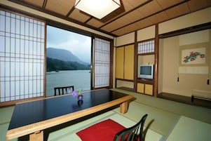 Una habitación tradicional japonesa con suelo de tatami, una mesa baja y vista a un río.