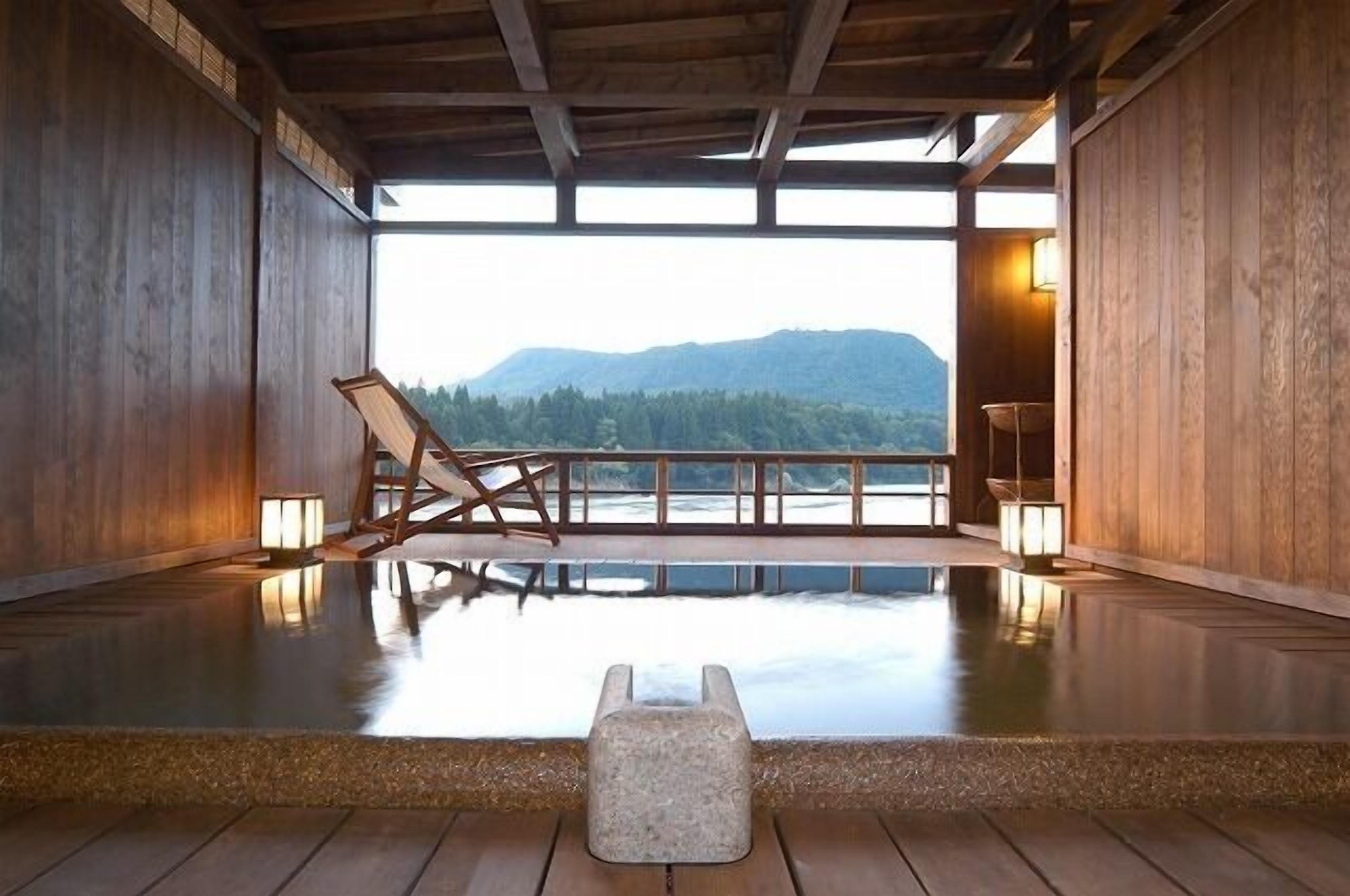 Un intérieur en bois avec vue sur les montagnes, un banc en bois et une petite table.