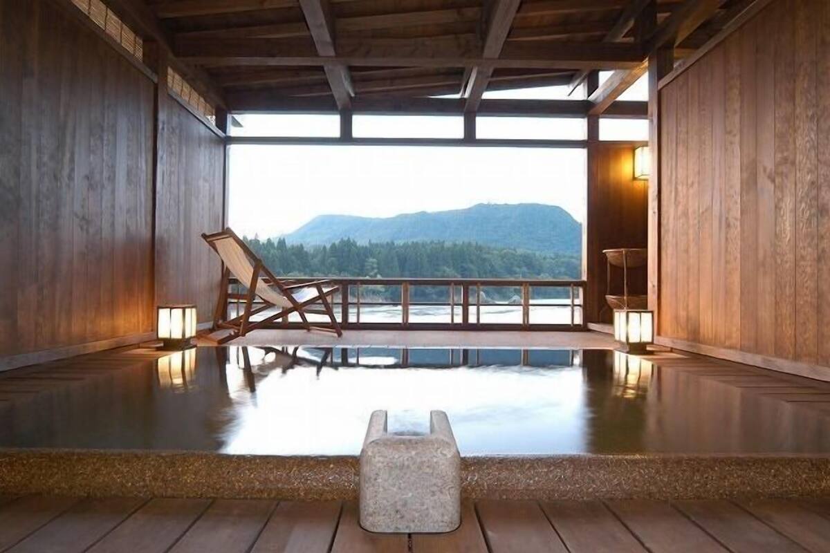 A wooden interior with a view of mountains, a wooden bench, and a small table.