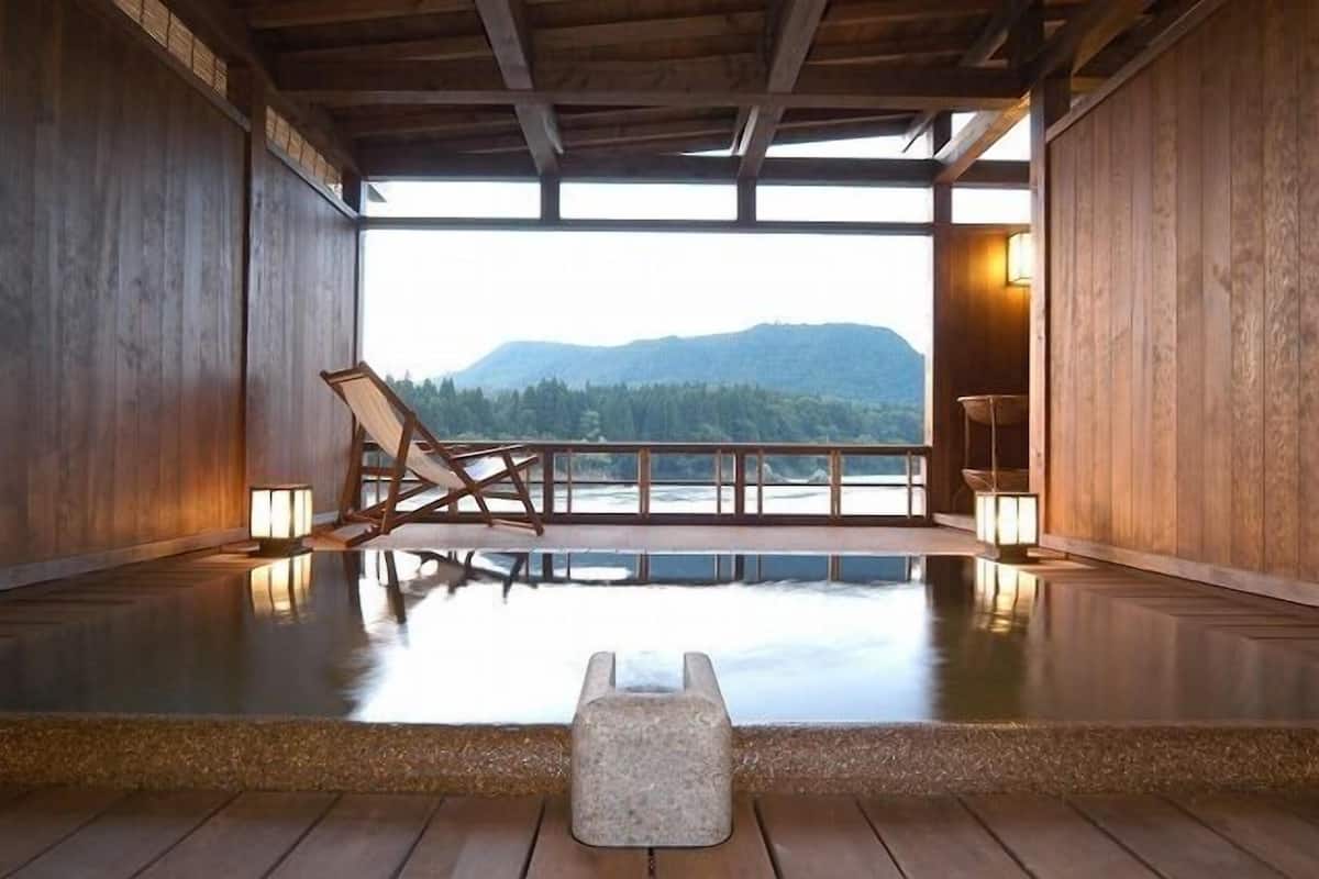 Un intérieur en bois avec vue sur les montagnes, un banc en bois et une petite table.