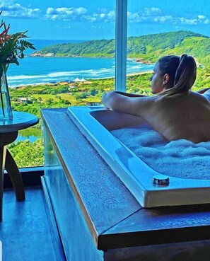 A person relaxing in a bathtub with a view of a coastal landscape. - Morada dos Sisais (Imbituba)