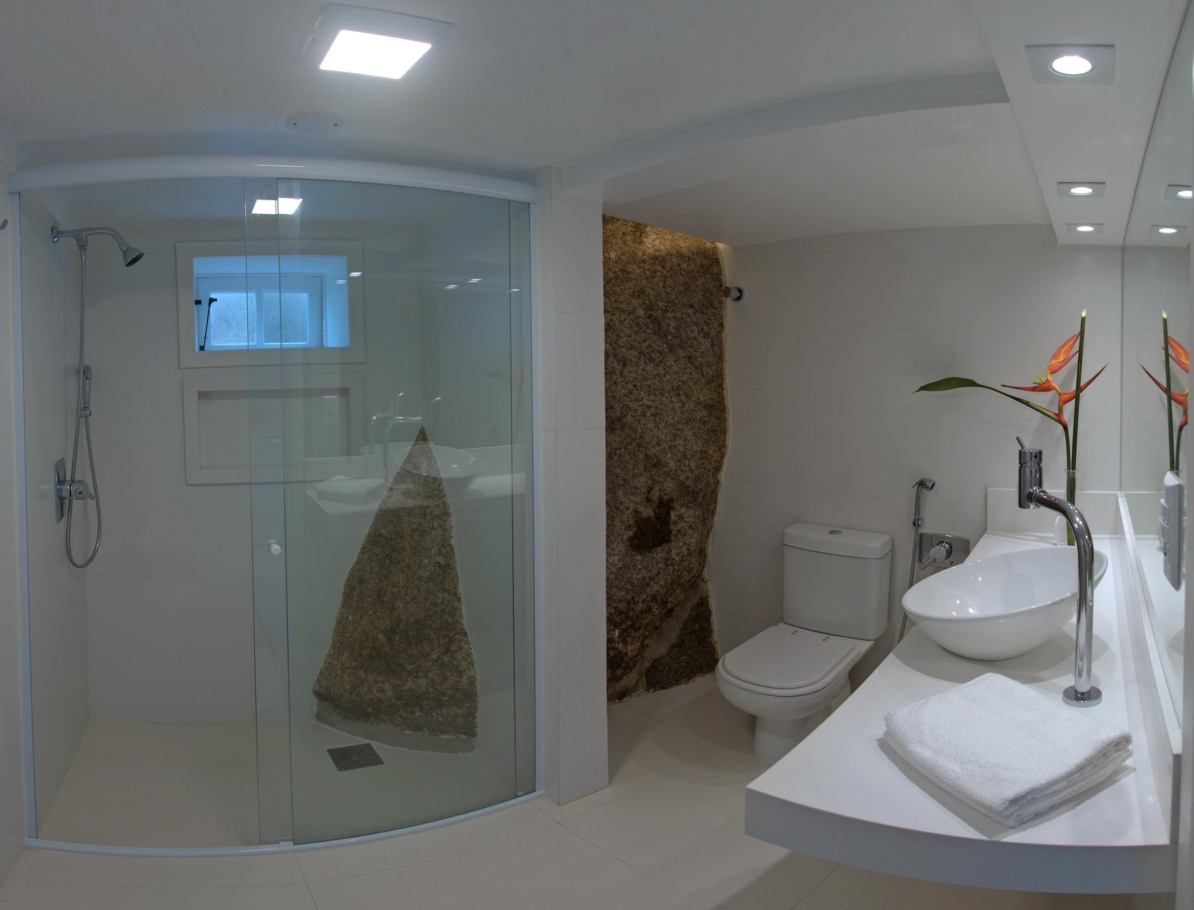 A modern bathroom with a glass-enclosed shower, a white toilet, and a sink with a towel on the counter.
