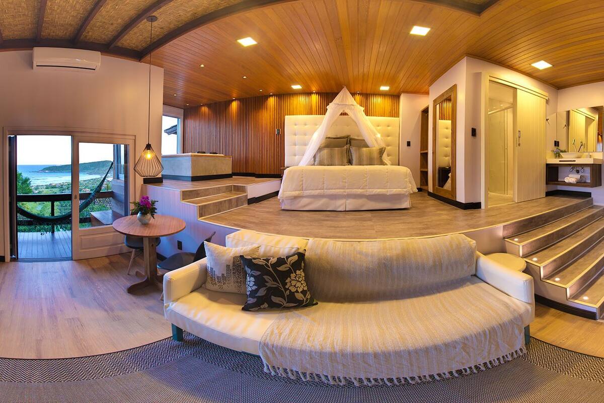A spacious living area with a curved sofa, a canopy bed, and a view of the outdoors.