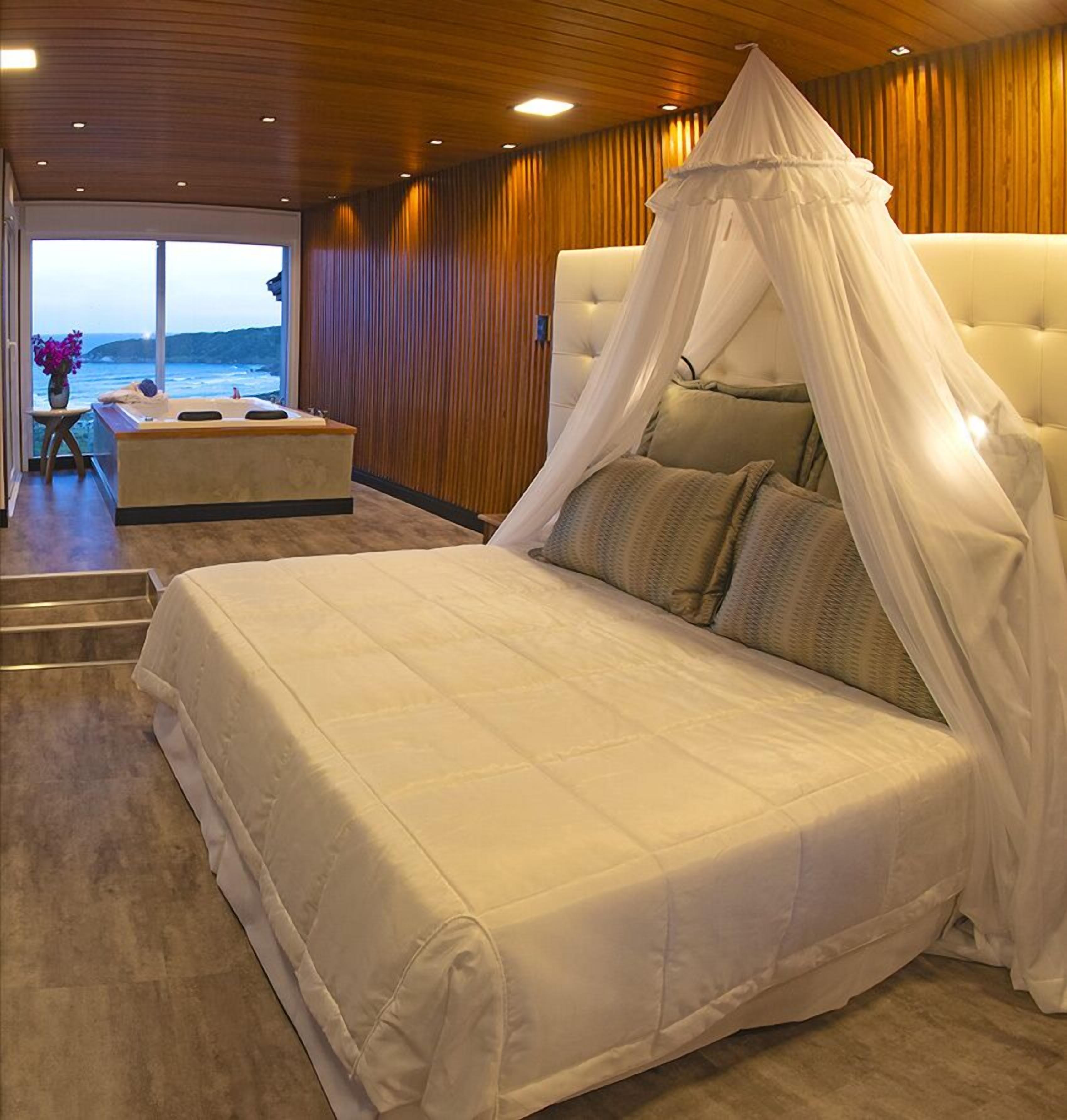 A bedroom with a large bed, a canopy, and a view of the ocean.