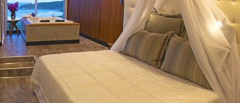 A bedroom with a large bed, a canopy, and a view of the ocean.