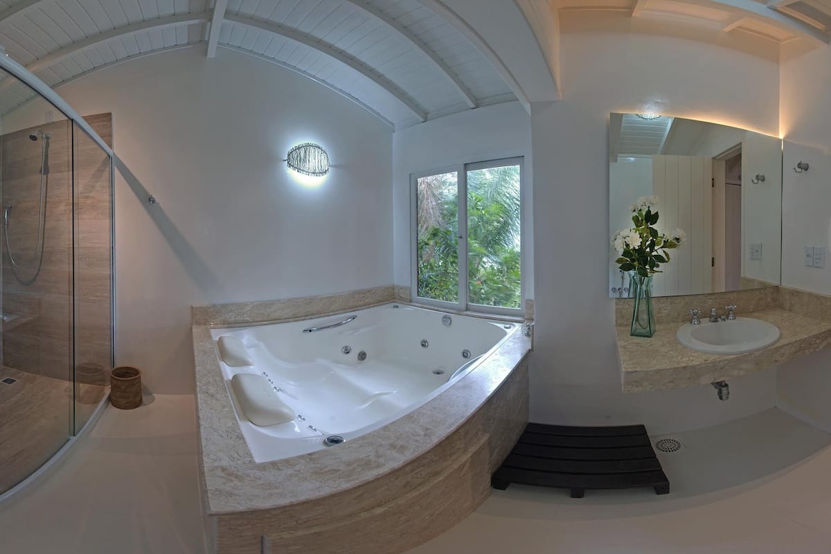 A modern bathroom with a freestanding bathtub, a glass-enclosed shower, and a large window providing natural light.