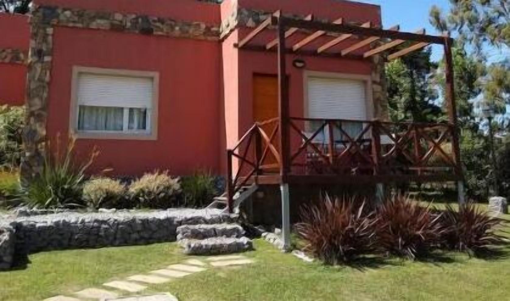 Un edificio rojo con un porche cubierto y escalones de piedra que conducen a una puerta.