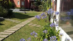 A garden pathway leading to a building with a red exterior and a white wall. - Icalma de la Sierra Apart Hotel Tandil (Tandil)