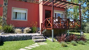 A red building with stone accents, a covered porch, and a stone pathway leading to the entrance. - Icalma de la Sierra Apart Hotel Tandil (Tandil)