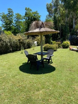 An outdoor seating area with a thatched umbrella, two chairs, and a table. - Icalma de la Sierra Apart Hotel Tandil (Tandil)