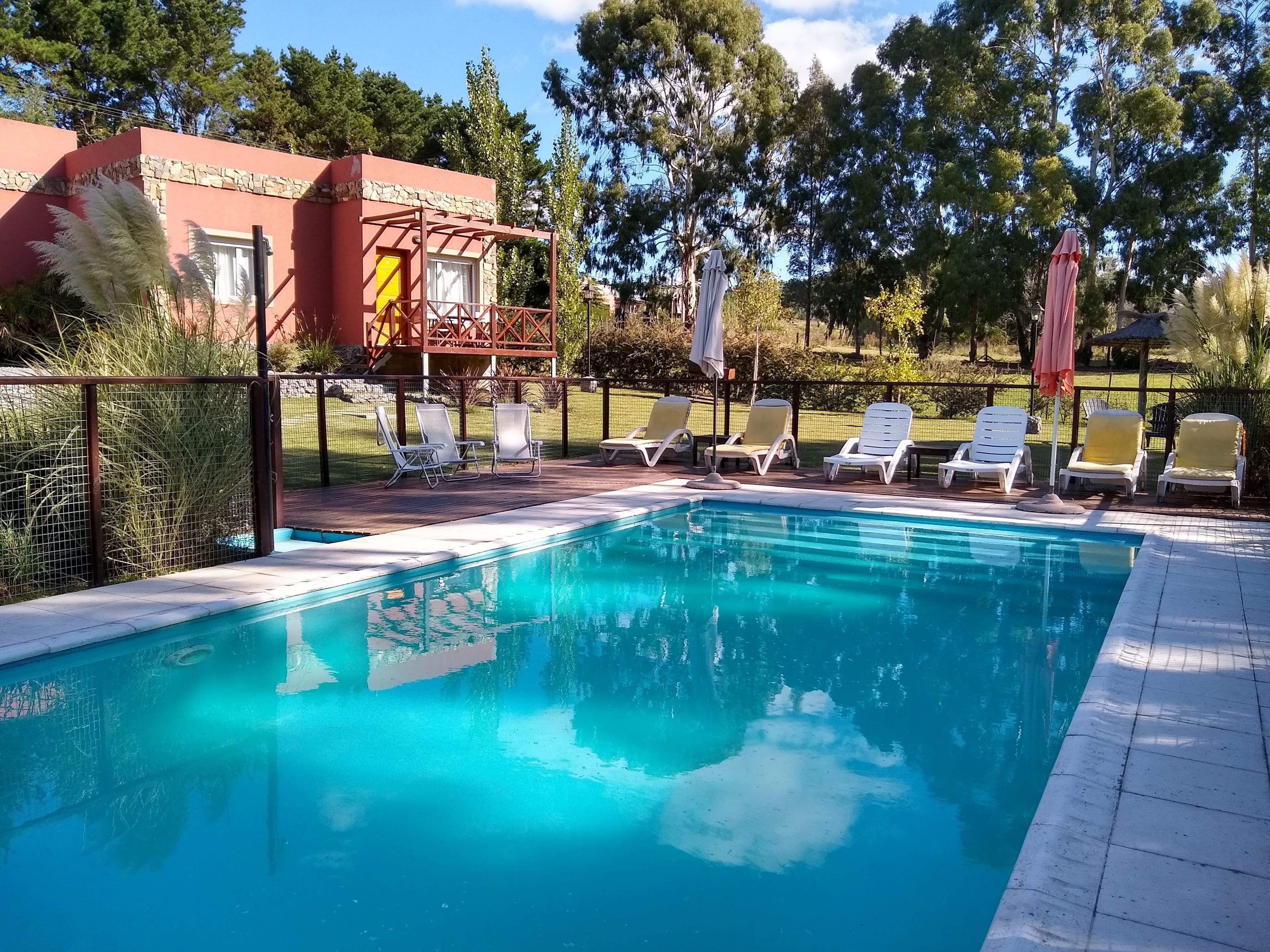 Una piscina con tumbonas y un edificio de piedra al fondo.