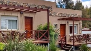 A two-story building with a stone facade, wooden balconies, and a small garden area with various plants. - Icalma de la Sierra Apart Hotel Tandil (Tandil)