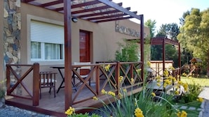 A covered patio with wooden furniture, a stone wall, and a playground structure. - Icalma de la Sierra Apart Hotel Tandil (Tandil)