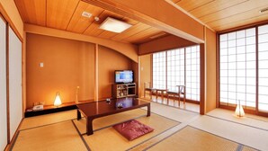 A traditional Japanese room with tatami flooring, a low wooden table, a television, and sliding doors. - Plaza Hotel Mutsu (Mutsu)