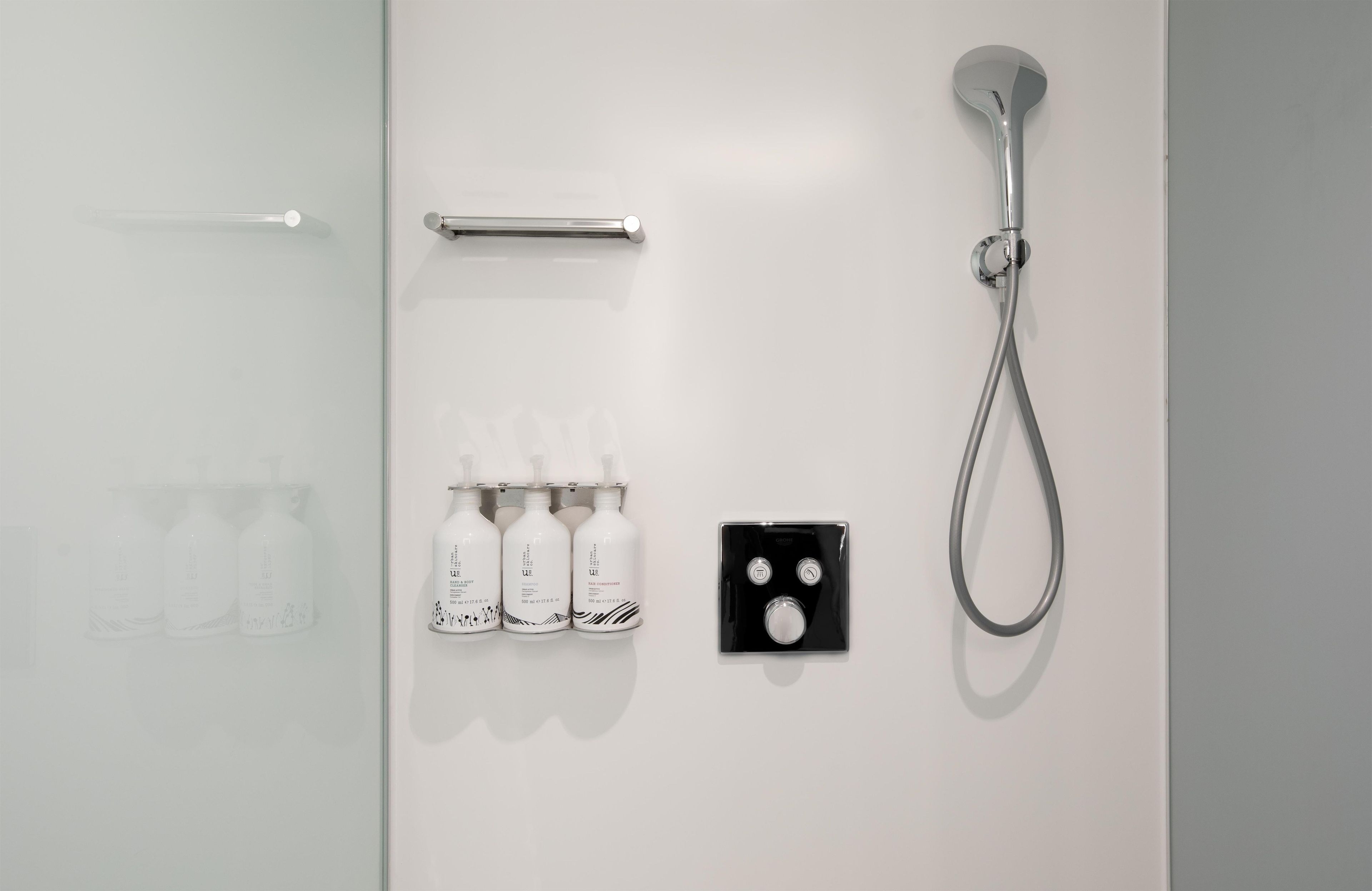 A bathroom with a shower, a towel rack, and a set of toiletries.