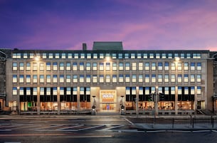A modern hotel with a flat roof, multiple floors, and a prominent entrance.