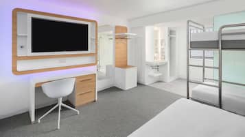 Un dormitorio moderno y bien iluminado con una cama individual superpuesta, un escritorio con silla, un televisor y un armario.