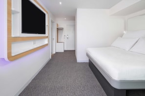 A modern hotel room with a flat-screen TV mounted on the wall, a bed with white bedding, and a grey carpeted floor. - YOTEL Edinburgh, Select by Hilton (Edinburgh)