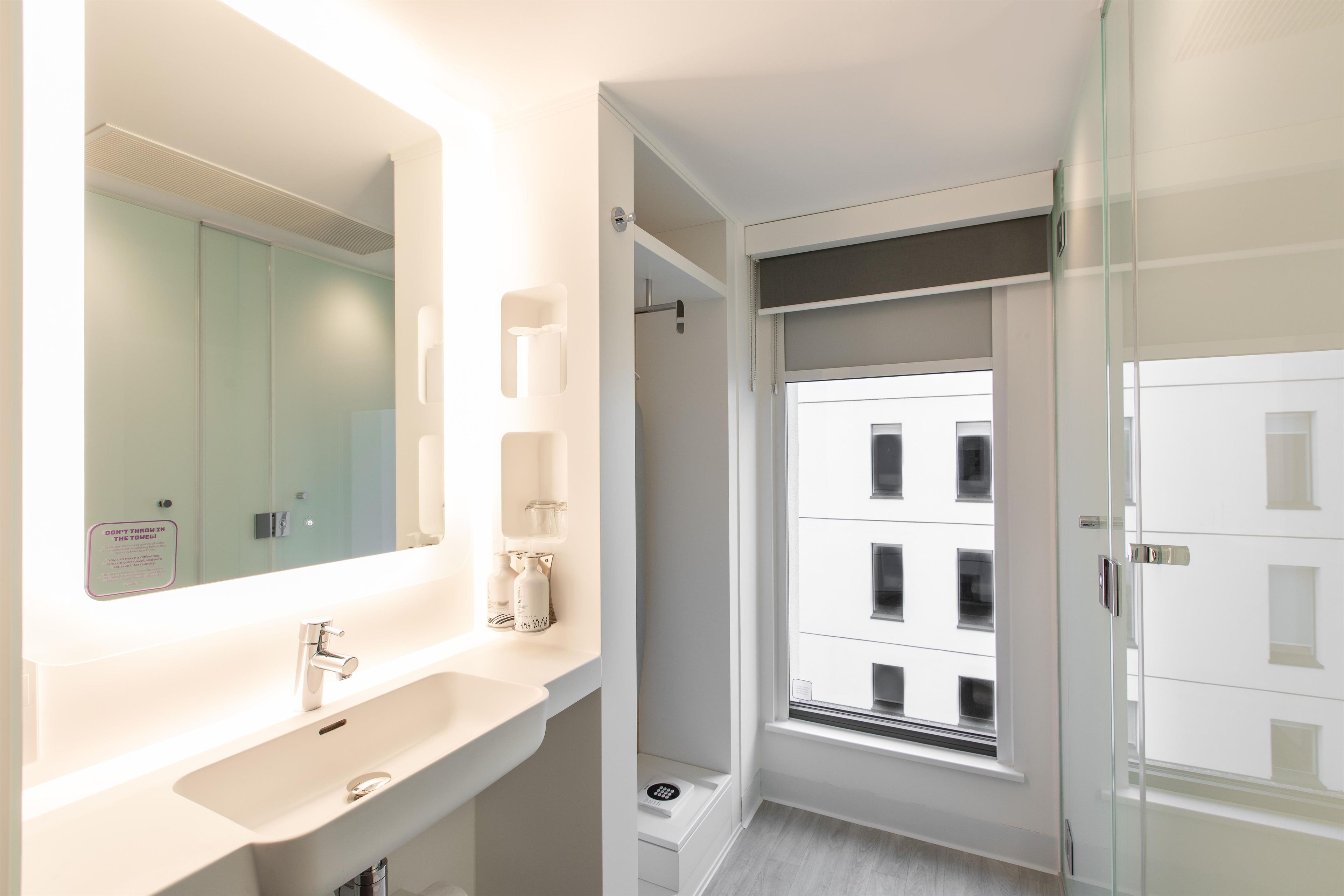 A modern bathroom with a large mirror, a sink, and a shower.